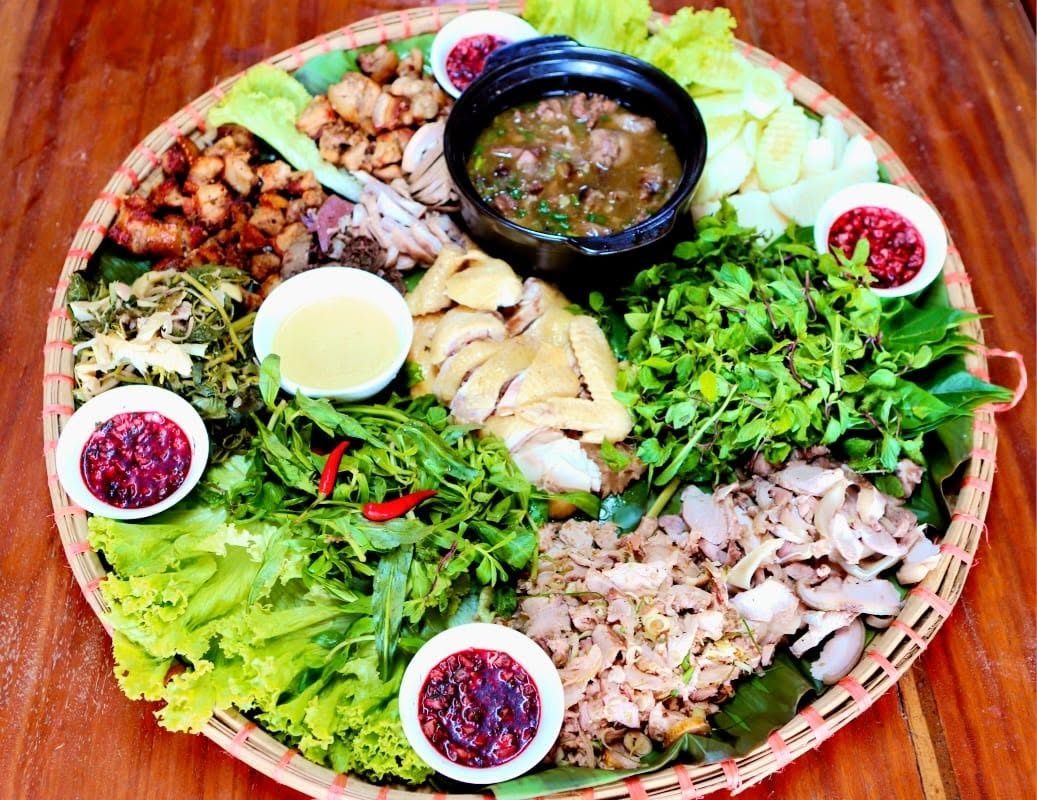 Mâm cỗ bản địa bày trên lá với thịt và rau thơm